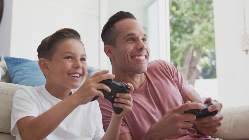 Hispanic father and son sitting on floor at home playing video game and giving each other high five - shot in slow motion | Shutterstock HD Video #1052420293