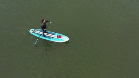 Aerial view of a man on a surfboard known as Sup, surfing at sea. Man stands firmly on an inflatable SUP board and rowing. Gdansk. Poland. 04. May. 2020.