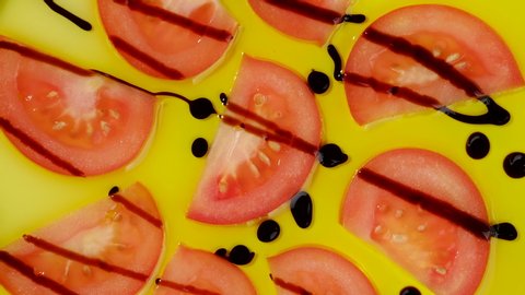 sliced red tomatoes with balsamic Modena in olive oil rotating. top view