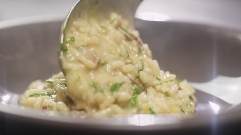 Serving of risotto with mushroom in a plate, slow motion.