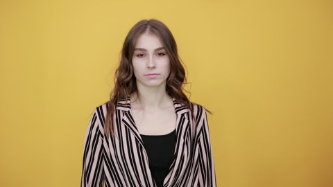 Cute Young Woman Light Brown In Striped Pink And Black Shirt On A Yellow Background, Annoyed Girl Shows Sign Fuck You, Shows Middle Finger