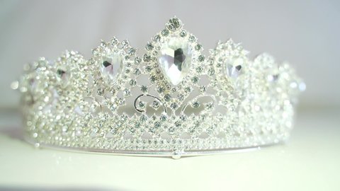 Diamond Crown of Beauty Pageant Contest, flare lighting movement. 
Close up of a tiara, shimmering light from diamonds, bokeh and sparkles in the sun on a white light background. Diadem. Shines silver