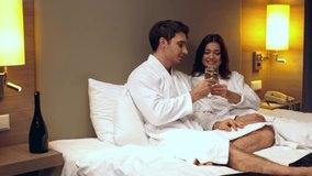 cheerful couple clinking champagne glasses while relaxing in hotel room