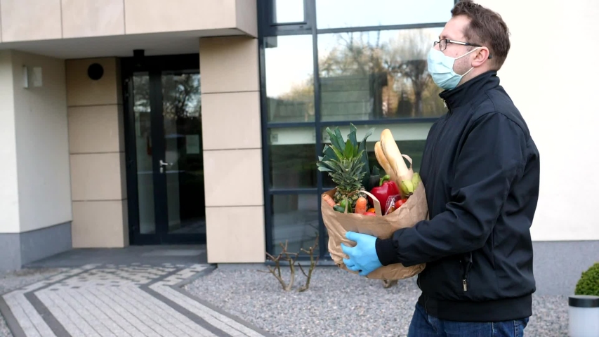 Courier protective mask medical gloves delivers groceries slow motion