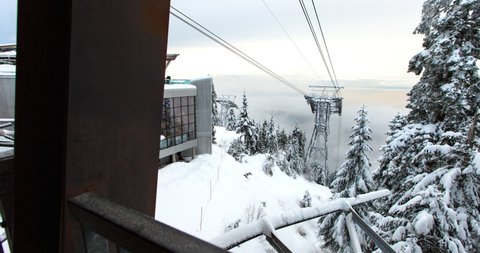 Panning time lapse shot of gondola lift by building over snowcapped mountain - Vancouver, Canada