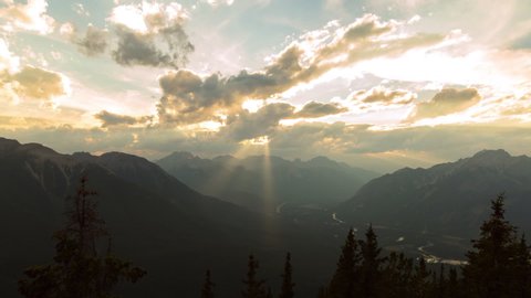 Lockdown time lapse shot of river amidst mountains against cloudy sky during sunrise - Banff, Canada