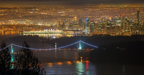 Lockdown time lapse shot of illuminated Lions Gate Bridge over sea by city at night - Vancouver, Canada