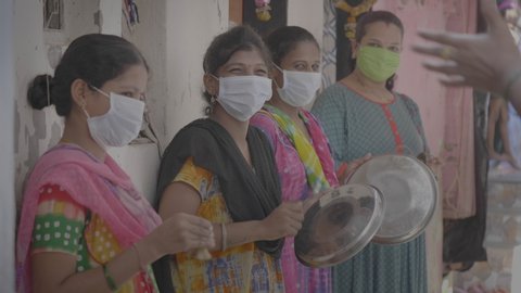 A group of women/ ladies wearing protective face mask and banging utensils/ plates/ clapping to show appreciation/ respect/ salute to health workers, doctors, nurses etc. Mumbai, India (May 2020)