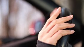 Video 4k footage, female hands hold the steering wheel of a car, beautiful fingers with a neutral manicure