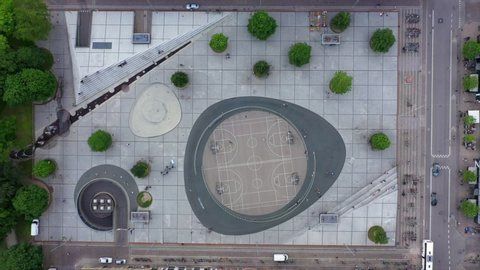 Aerial lockdown shot of people on basketball court at town square, drone flying on top of footpath in city - Copenhagen, Denmark