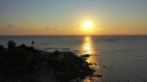 Aerial shot of sun with reflection on sea against sky at sunset, drone flying forward towards horizon - Montevideo, Uruguay