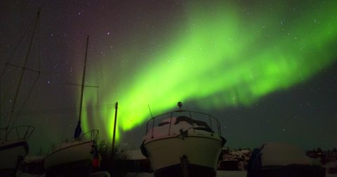 Time lapse shot of snow covered boats against Aurora Borealis at night - Northwest Territories, Canada