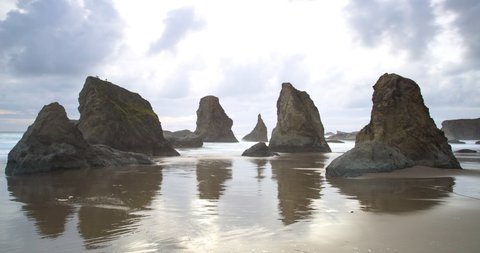 Time lapse shot of waves splashing on stack rocks at Bandon Beach against cloudy sky