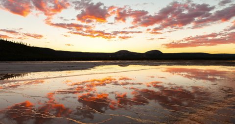 Lockdown time lapse shot of clouds reflection on Grand Prismatic Spring against sky during sunset - Yellowstone National Park, Wyoming