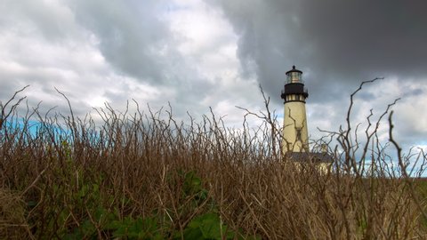 Panning time lapse shot of Yaquina Head Lighthouse by plants against sky - Newport, Oregon