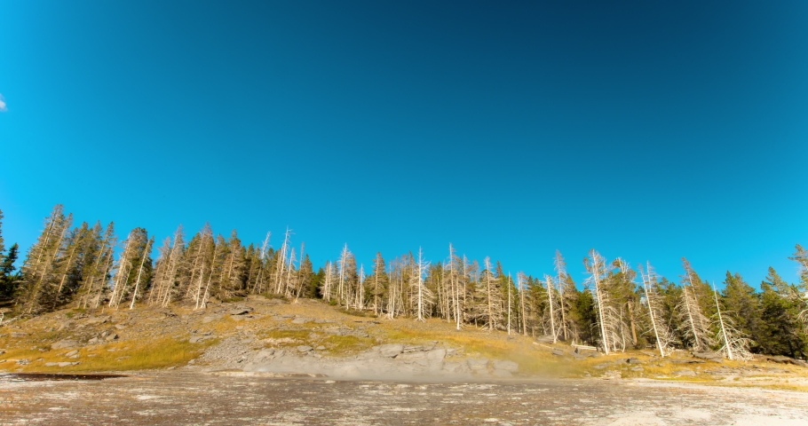 Lockdown shot of rainbow over Grand Geyser splashing at national park on sunny day - Yellowstone National Park, Wyoming