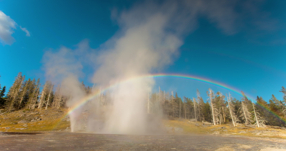 Time Lapse shot of rainbow over Grand Geyser splashing at national park on sunny day - Yellowstone National Park, Wyoming