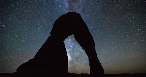 Time lapse shot of silhouette Delicate Arch in desert against Milky Way at night - Arches National Park, Utah