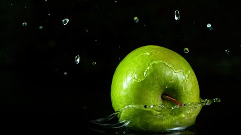 Super Slow Motion Shot of Fresh Green Apple Falling into Water Isolated on Black Background at 1000fps.
