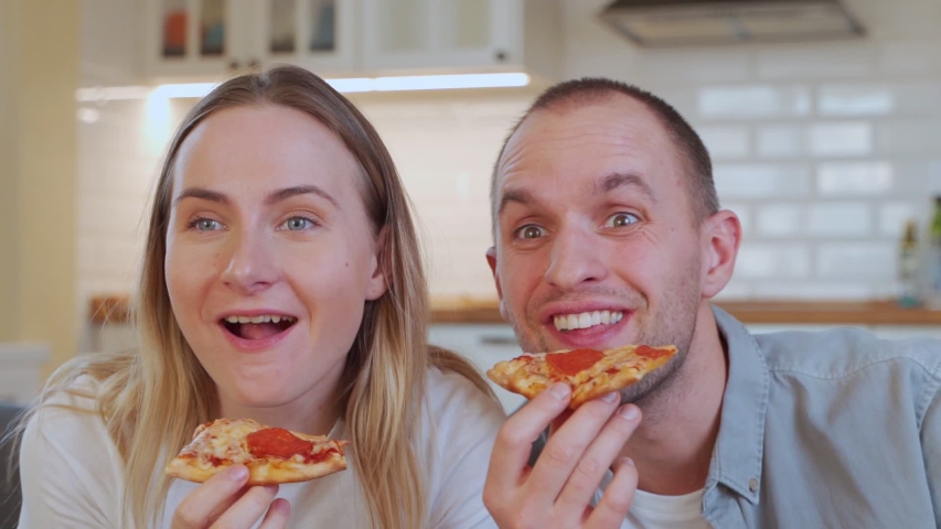Couple relaxing, watching TV and eating pizza at home. | Shutterstock HD Video #1052461321
