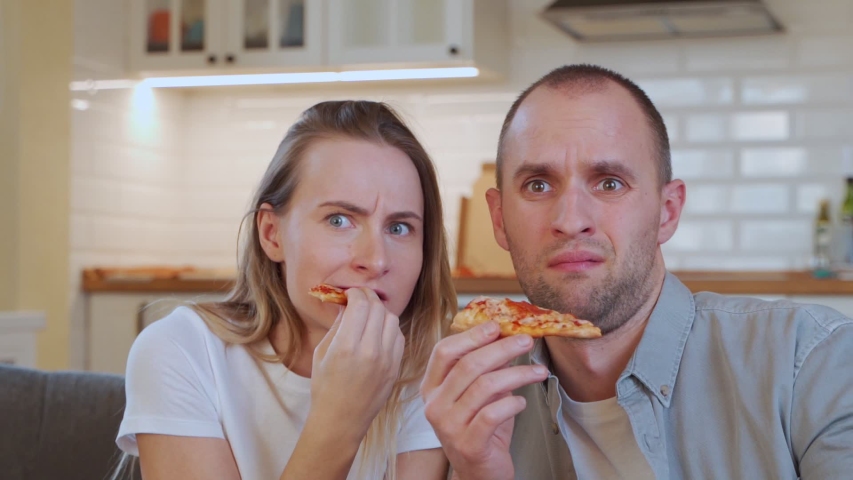 Couple relaxing, watching TV and eating pizza at home. | Shutterstock HD Video #1052461324