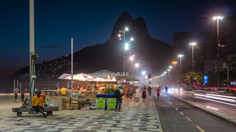 Rio de Janeiro, Brazil - November 22: Night timelapse view of people walking on the mosaic sidewalks along Ipanema Beach in Rio de Janeiro, Brazil.