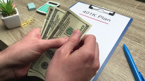 401k retirement plan, a man counts 100 dollar bills at a wooden table