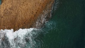Nostalgic aerial video, in slow motion of the sea, the waves smoothly roll on the rocky shores of the Pacific Atlantic Ocean.