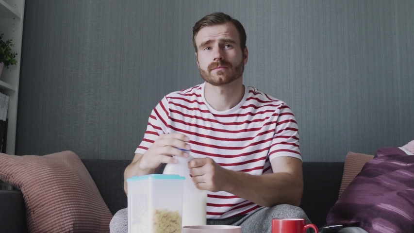 Bearded man pours milk into a cup to preparing breakfast