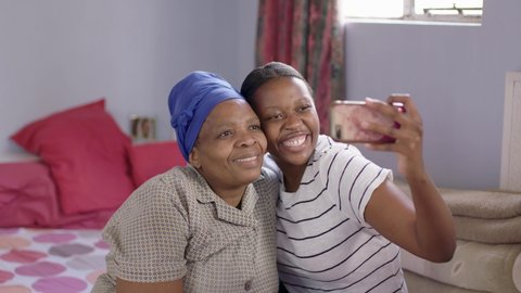 Black South African mother and daughter taking selfies together at home.