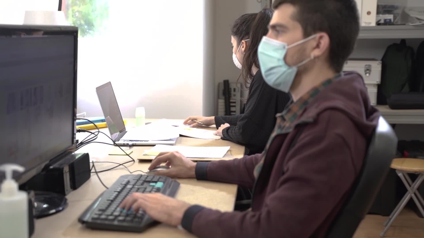 Coronavirus. Business workers working from home wearing protective mask. Small company in quarantine for coronavirus working from home with sanitizer gel. Small company concept. | Shutterstock HD Video #1052480311