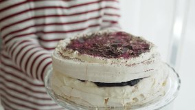Woman holding plateu with white Meringue cake with forrest fruits, berries and chocolate. Slow motion video