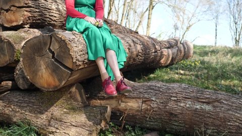 Woman dangling legs sitting on tree trunks