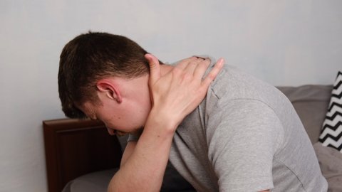 Side view of upset tired young man wear t-shirt feels pain in neck in morning after sleeping, awaken in bad temper having painful sudden ache or stiffness. Fibromyalgia concept
