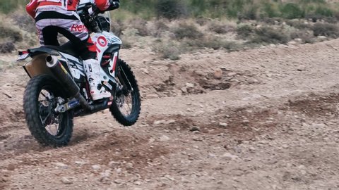 Teruel/Spain - July 27 2019: Baja, Aragon. Dirt bike driving through muddy puddles, slow motion. Motorbike passing by, splashing mud and water. Bike Race Rally.