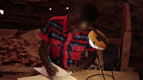 Embu/Kenya 10/‎23/‎2018 : A child in rural Africa Studying under an solar powered lamp. A child in rural Africa studying in a mud house. A child in rural Africa studying under bad condition