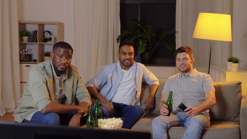 Friendship, leisure and people concept - happy male friends with beer and popcorn watching tv at home at night | Shutterstock HD Video #1052491789