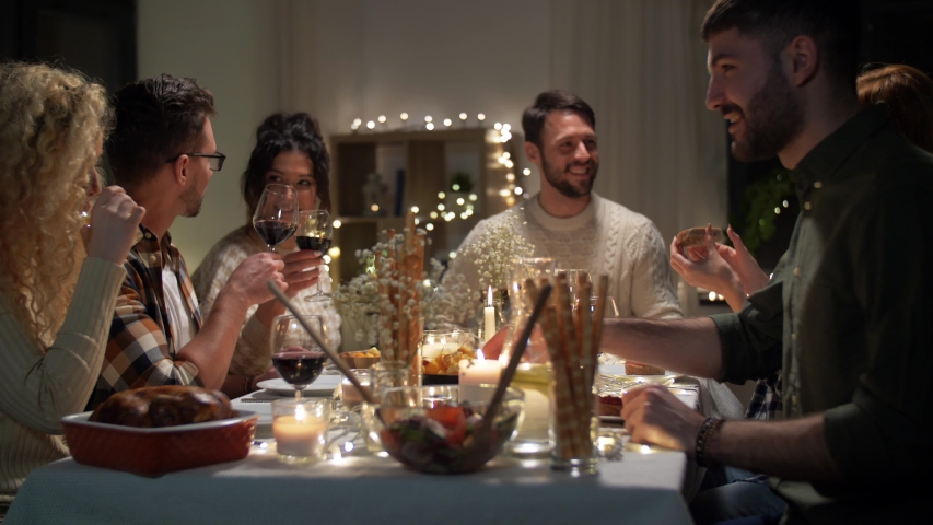 holidays, celebration and people concept - happy friends having christmas dinner party and drinking non-alcoholic red wine at home