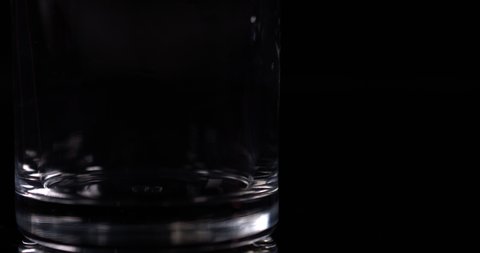 Macro milk splashing pouring into a glassful on a black background in slow motion