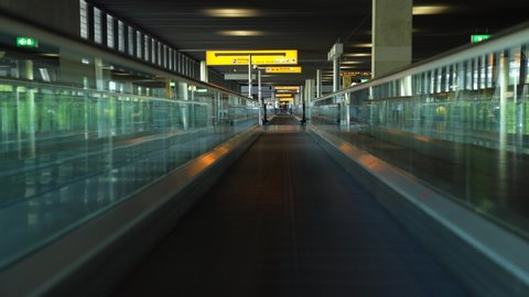 Schiphol Airport, Netherlands - May 9 2020: Empty moving sidewalk or walkway in Schiphol Amsterdam airport terminal due to coronavirus pandemic lockdown no people but very clean surfaces and silence. 