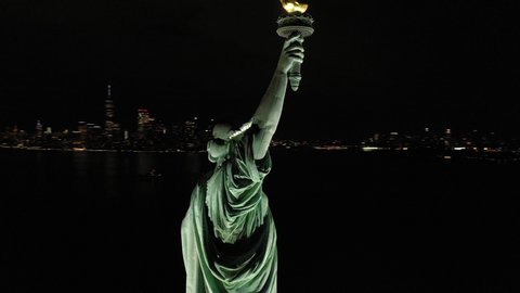 NEW YORK - CIRCA 2020 - An excellent orbiting aerial view shows the upper half of the Statue of Liberty in New York City, New York at night.
