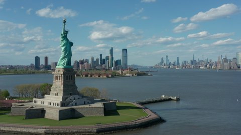 flying clockwise around Statue of Liberty w NYC in bkrd