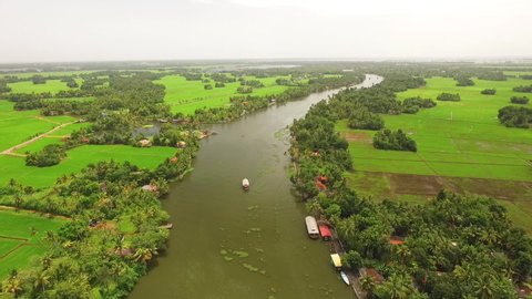 KERALA, INDIA - CIRCA 2020 - An aerial view shows a houseboat sailing down a river in Kerala, India.