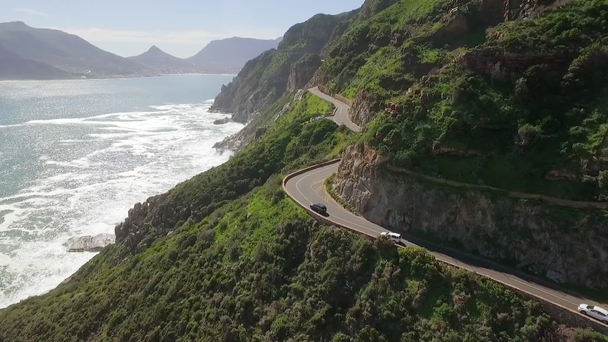 SOUTH AFRICA - CIRCA 2020 - An aerial view shows cars are seen driving by the seaside along Chapman's Peak in South Africa. Royalty-Free Stock Footage #1052517979