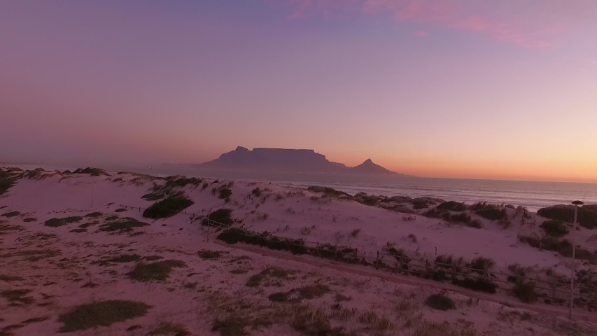 CAPE TOWN, SOUTH AFRICA - CIRCA 2020 - Table Mountain is seen at sunset from the coast of Bloubergstrand in Cape Town, South Africa.