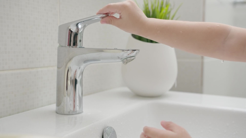 A small child learns to open a tap with water and wash his hands. Close-up Royalty-Free Stock Footage #1052524672
