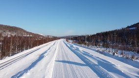 Video of flight on the copter over a road covered with snow in winter on a bright Sunny day. The road is covered by a layer of compact snow. Video shot at the copter from the height of 20-30 meters.