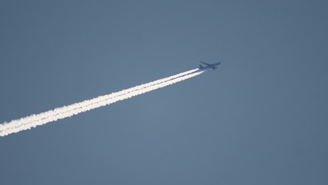 Widebody airplane flying at high altitude with contrail
