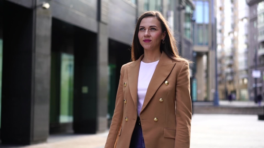 charming brunette woman is throwing her coat on camera playfully, walk in city