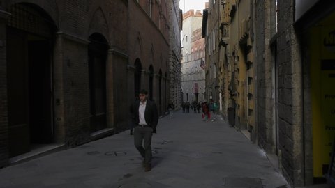 SIENA, ITALY - FEBRUARY 25, 2020: People walk along a pedestrian street in ancient Siena. Tuscany, Italy.